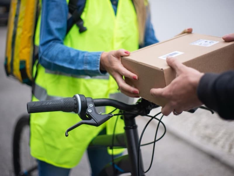 Fahrradkurier übergibt ein neutrales Paket